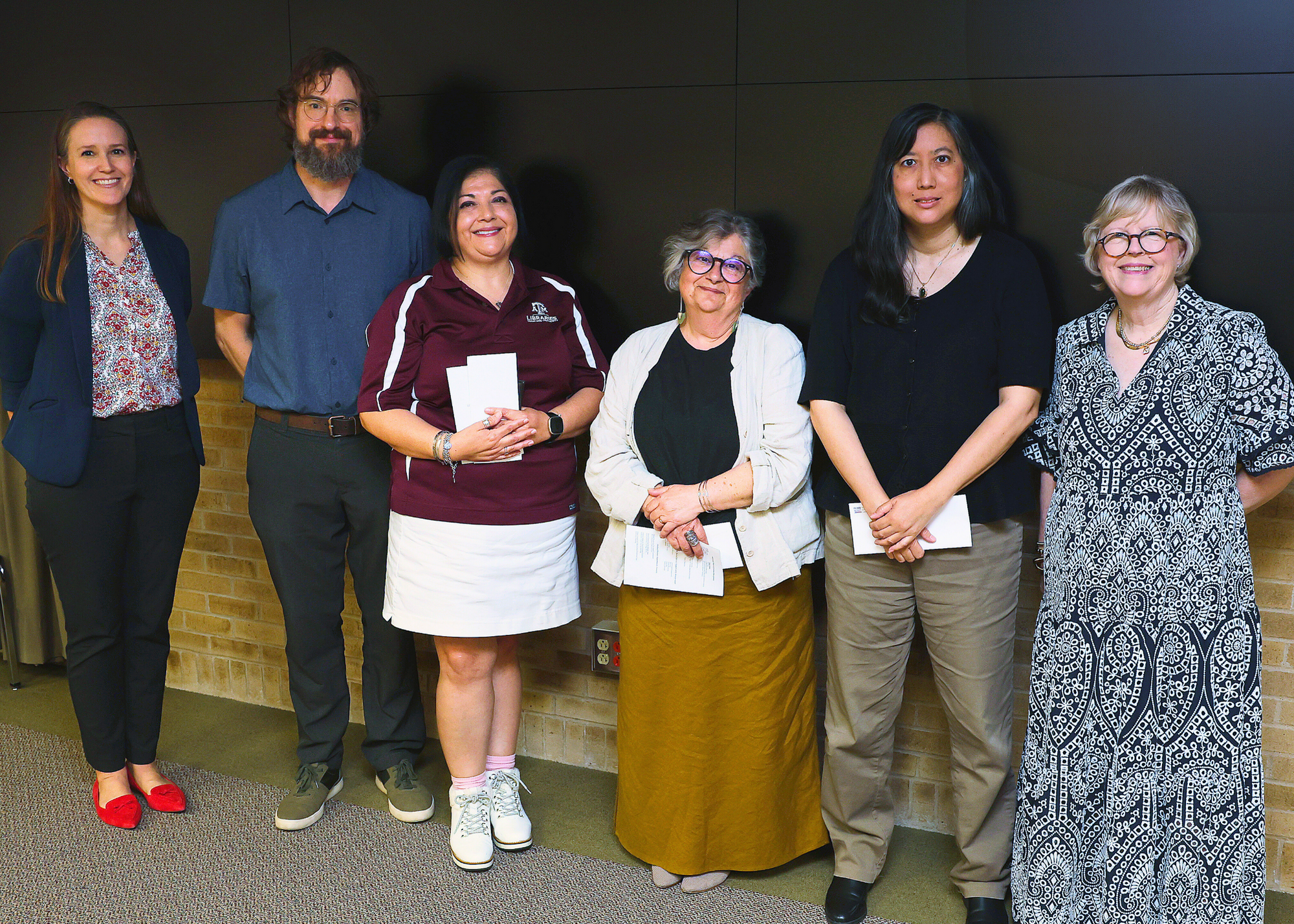 Longevity service award winners standing between the University Librarian and a representative from the Friends of the Texas A&M University Libraries.